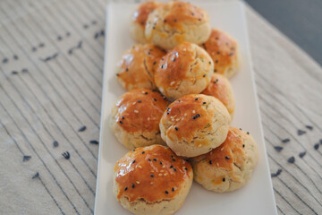 turkish savory pastry pogaca with dill and black sesame or cumin, homemade quick snack served on darck table and table cloth