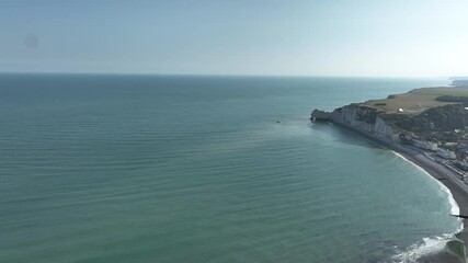 Aerial view of the dramatic Étretat Cliffs meeting the turquoise sea, where white chalk cliffs contrast with the dark beach, Étretat, Normandy, France. - Powered by Adobe
