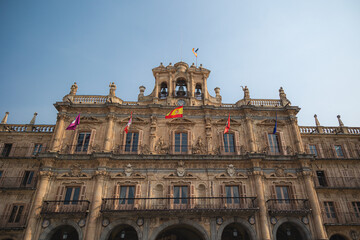 Baroque Façade of Salamanca City Hall on Plaza Mayor with Flags and Sculptures Under Clear Blue Sky