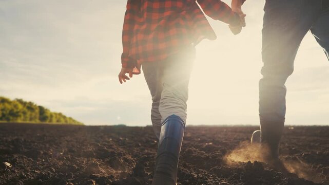 Two people walking in a field. Father walking his son through the legs of farmers. Farmers walk on the field with their families. A couple strolling through lifestyle a meadow.