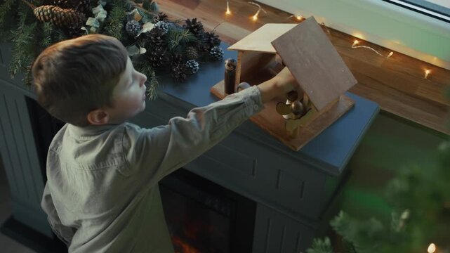 Child arranging wooden nativity scene on fireplace mantelpiece for christmas