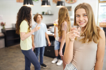 Smiling teenagers enjoying drinks together in a school cafeteria setting
