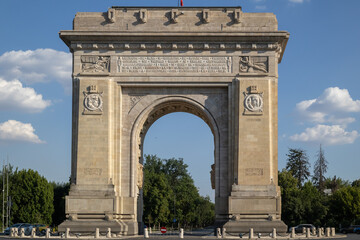 Obraz premium The Arcul de Triumf stands proudly on a sunny day in Bucharest, Romania. This historic arch honors Romanian soldiers of World War I