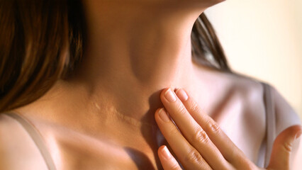 Close-up of an unrecognizable woman touching her neck. Endocrine health prevention. Diseases of the thyroid gland. Cancer screening. Endocrinology. Concept of medicine and health care. Self care
