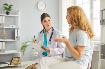 Fototapeta premium Caring young female nurse, doctor, caretaker talking. assisting helping woman patient in rehabilitation recovery during medical checkup visit for healthcare, examination, caregiver chatting to support