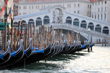 Venetian gondolas moored at the quay, with a view of the Rialto Bridge in the background, Venice, Italy