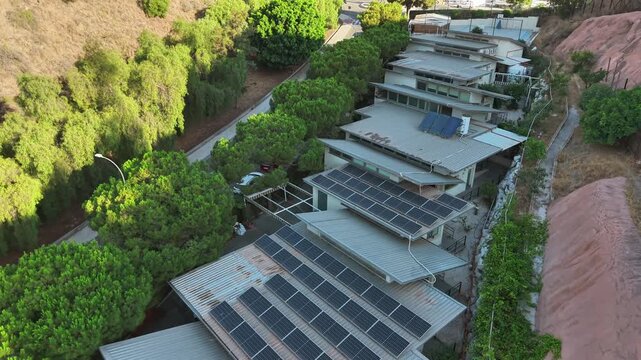 An aerial drone shot shows a modern building with a rooftop pool on Vicente Paul street in Spain. The scene features a blend of traditional and contemporary architecture, highlighting a unique urban