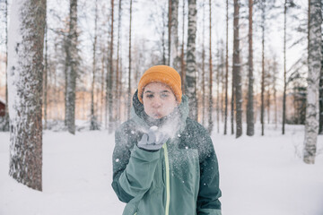 Fototapeta premium Young girl blowing snow in a winter forest