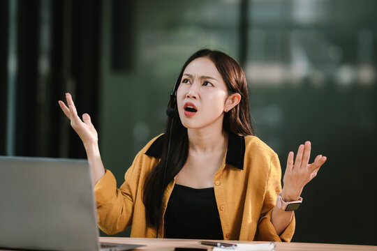 An overworked woman wearing a headset sits in an office call center, stressed and frustrated while working on her computer, facing deadlines, pressure, and workplace challenges.
