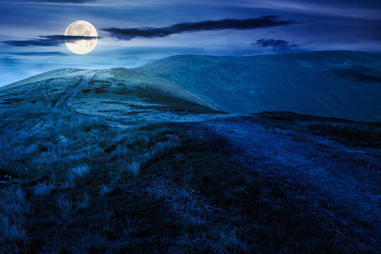 path for mountain tourism in summer at night. alpine landscape. beautiful scenery of ridge with green hills under blue sky with clouds in full moon light