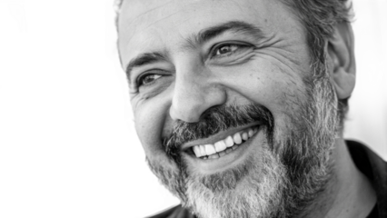 Close up black and white shot of a smiling man with a beard looking to the side of the frame