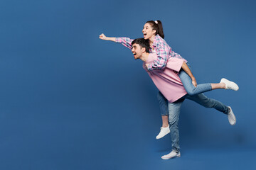 Fototapeta na wymiar Full body young couple two friends family man woman wear pink casual clothes together give piggyback ride to joyful, sit on back run pov super hero isolated on plain blue background Lifestyle concept