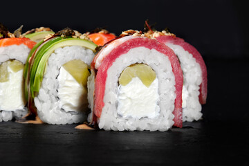 Delicious uramaki sushi rolls covered with tuna and avocado presenting filling of cream cheese and cucumber