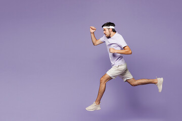Full body side view young strong fitness trainer instructor sporty man sportsman wear sportswear train in home gym jump high run fast isolated on plain purple background Workout sport fit abs concept