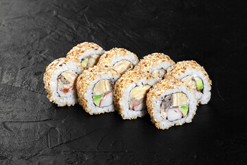Delicious sushi rolls covered in sesame seeds on black background