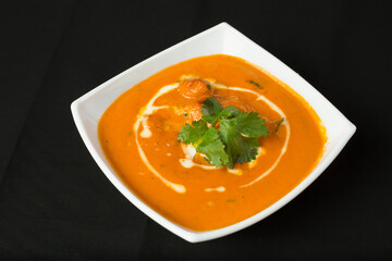 Creamy Butter Chicken or Murgh Makhani in bowl on dark background side view of a Classic Indian Curry with a Swirl of Cream