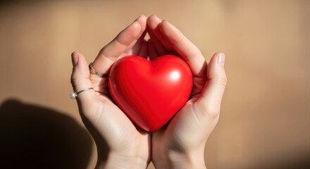 Woman's hands tenderly holding a vibrant red heart, symbolizing love and compassion