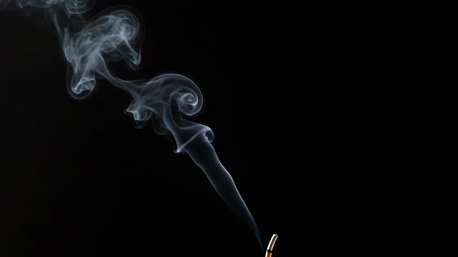 Smoke rising from incense stick on black background
