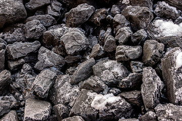 A pile of hard coal under snow, selective focus