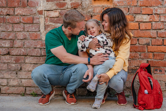 Happy family with child girl at the brick wall outside