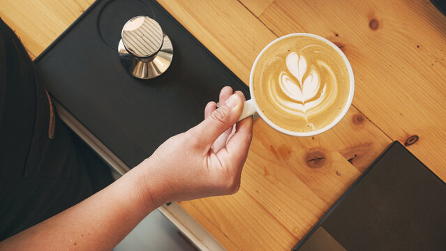 Barista hand with coffee cup, isolated cafee shop background.