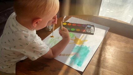 Little boy painting in sunny room with watercolors and brushes, close up view. Playing at home with child, early development of fine motor skills and drawing with toddler - Powered by Adobe