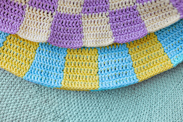 two crochet yellow and blue, violet squares in checkerboard pattern on green crochet background