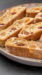 Italian Almond Biscotti biscuits in a rustic home made pottery bowl. Studded with almonds and cranberries, these twice-baked treats are aromatic and inviting. Ideal.
