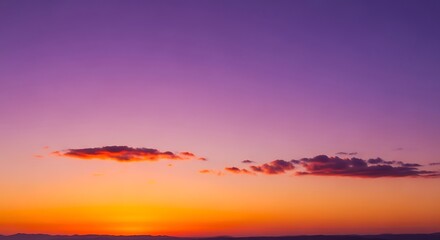 Fototapeta premium Vibrant sunset sky with orange and purple hues, featuring small, fluffy clouds.