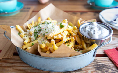 Crispy french fries topped with cheese and herbs served with a creamy dip at a casual eatery