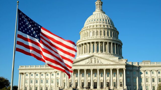 American Flag Waving at US Capitol Building - A large American flag waves proudly in the foreground, with the iconic US Capitol building in the background under a clear blue sky.