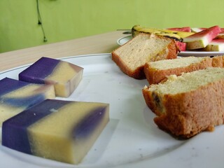 Slices of sponge cake and colorful layered pudding served on a white plate, perfect concept of sweet treats and dessert time.