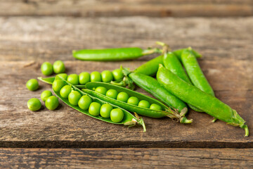 Fresh green pea pods with green peas on a wooden background. Sweet green peas. Green pea beans vegetables. Vegan. healthy vegetable. Copy space
