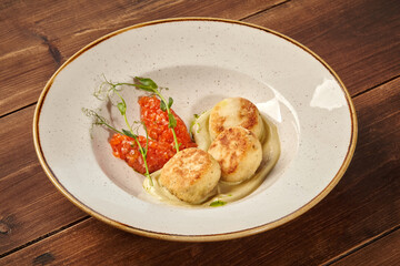 Delicious chicken cutlets with mashed potatoes and vegetable sauce lying on white plate on wooden table