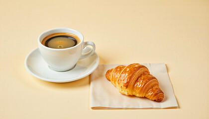 Cup of black coffee with croissant on napkin over beige background