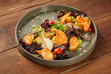 Delicious caesar salad with chicken, croutons, parmesan, and cherry tomatoes on rustic wooden table