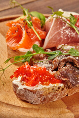 Chef preparing delicious bruschetta with salmon, prosciutto, and roast beef toppings