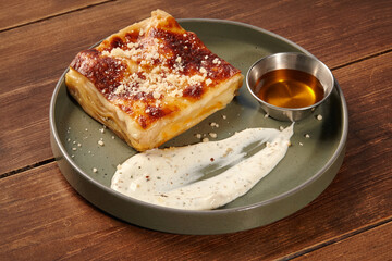 Delicious lasagna bolognese with honey and white sauce on wooden table