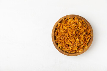 Crispy fried onions in a bowl on a wooden table. Roasted Onions. Seasoning for dishes. Spices. Salad dressing. Space for text. Copy space