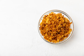 Crispy fried onions in a bowl on a wooden table. Roasted Onions. Seasoning for dishes. Spices. Salad dressing. Space for text. Copy space