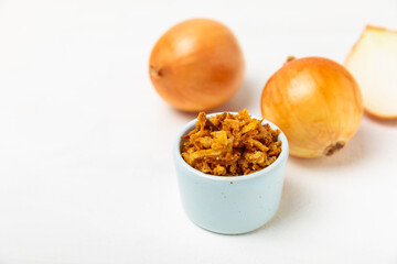 Crispy fried onions in a bowl on a wooden table. Roasted Onions. Seasoning for dishes. Spices. Salad dressing. Space for text. Copy space