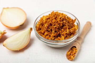 Crispy fried onions in a bowl on a wooden table. Roasted Onions. Seasoning for dishes. Spices. Salad dressing. Space for text. Copy space