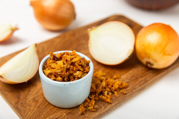 Crispy fried onions in a bowl on a wooden table. Roasted Onions. Seasoning for dishes. Spices. Salad dressing. Space for text. Copy space