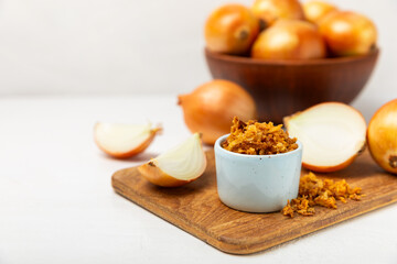 Crispy fried onions in a bowl on a wooden table. Roasted Onions. Seasoning for dishes. Spices. Salad dressing. Space for text. Copy space