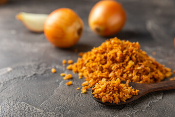 Crispy fried onions in a bowl on a wooden table. Roasted Onions. Seasoning for dishes. Spices. Salad dressing. Space for text. Copy space