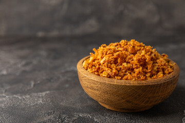 Crispy fried onions in a bowl on a wooden table. Roasted Onions. Seasoning for dishes. Spices. Salad dressing. Space for text. Copy space