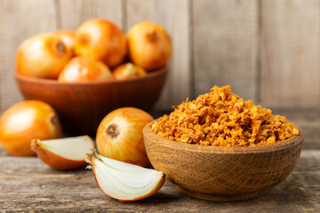 Crispy fried onions in a bowl on a wooden table. Roasted Onions. Seasoning for dishes. Spices. Salad dressing. Space for text. Copy space