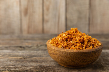 Crispy fried onions in a bowl on a wooden table. Roasted Onions. Seasoning for dishes. Spices. Salad dressing. Space for text. Copy space