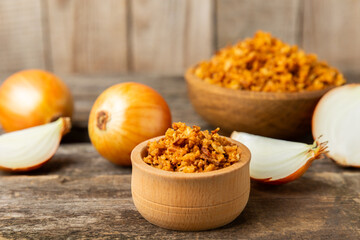 Crispy fried onions in a bowl on a wooden table. Roasted Onions. Seasoning for dishes. Spices. Salad dressing. Space for text. Copy space