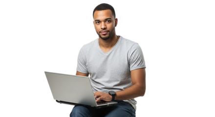 Man with gray shirt sitting and using a laptop in front of a black background looking at the viewer